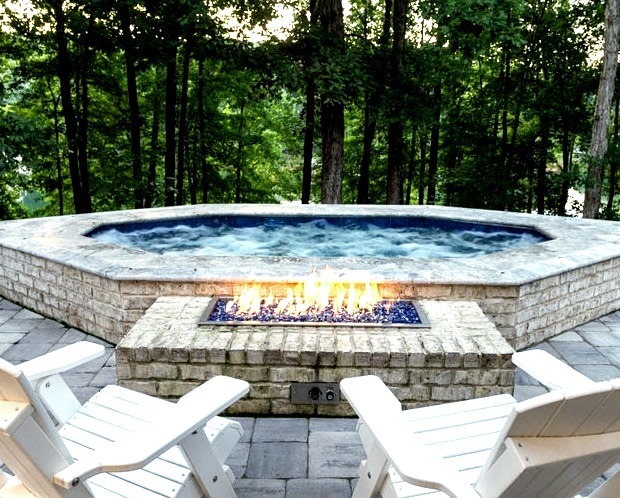Large transitional backyard brick and naturally shaped hot tub design